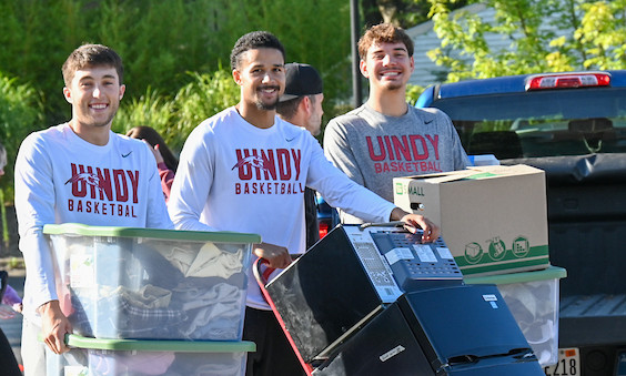 students carrying fridge and boxes during move-in