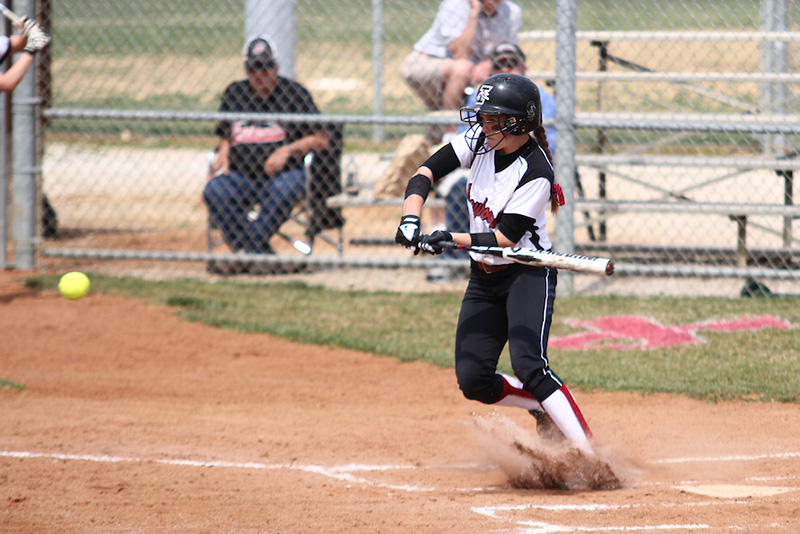 woman swinging a bat at softball game
