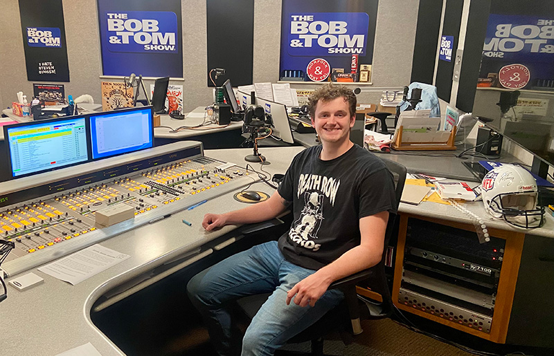 student sitting near the sound board at the Bob & Tom radio show