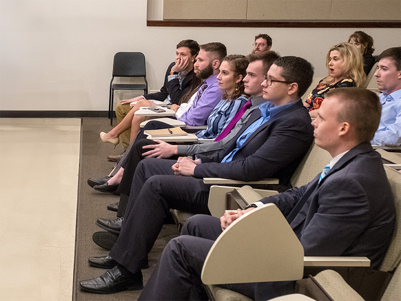 students in professional attire listening to a lecture