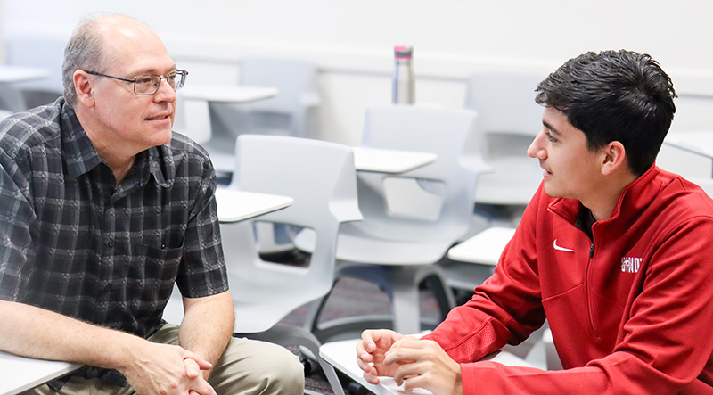 history professor on a one-on-one meeting with a student in the classroom