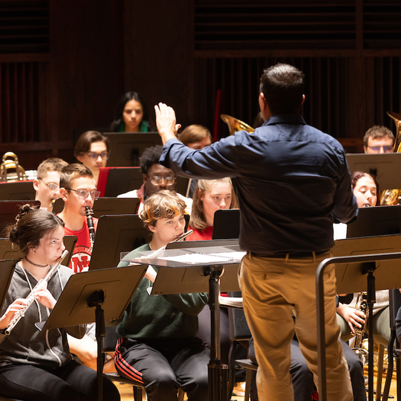 group of student playing music led by a conductor