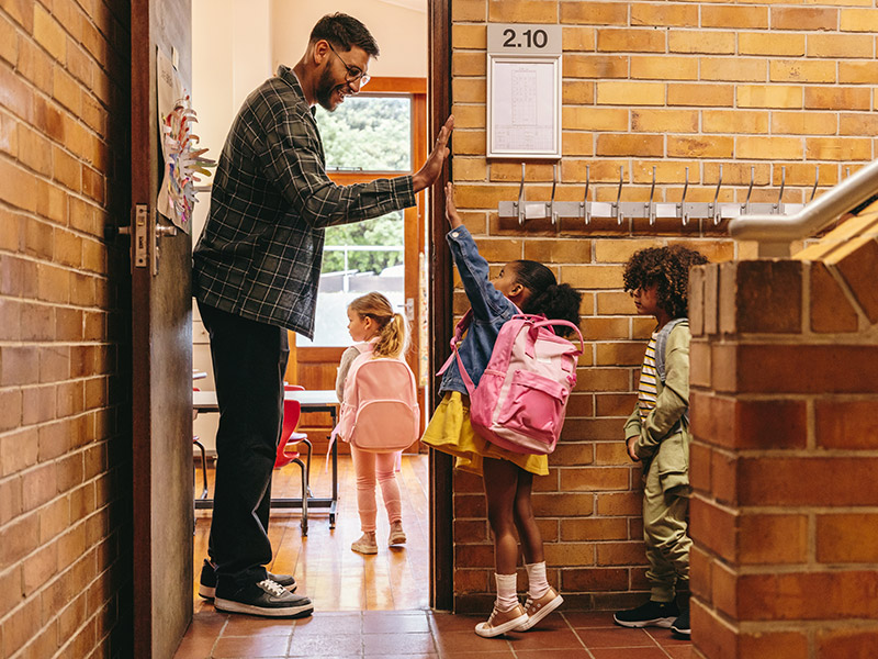 teacher welcoming kids, giving high fives