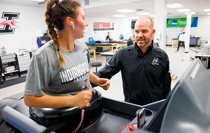 a student is on the anti-gravity treadmill and talking to an athletic training faculty member