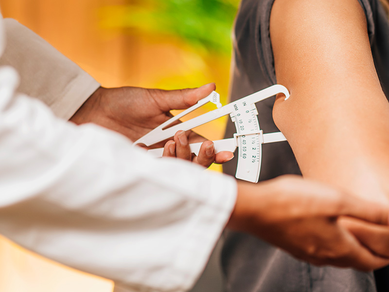 a health professional uses a body fat measurement tool on a patient's arm