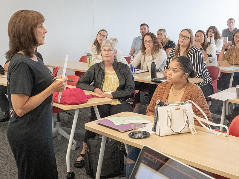 a professor teaches class while doctoral students look on