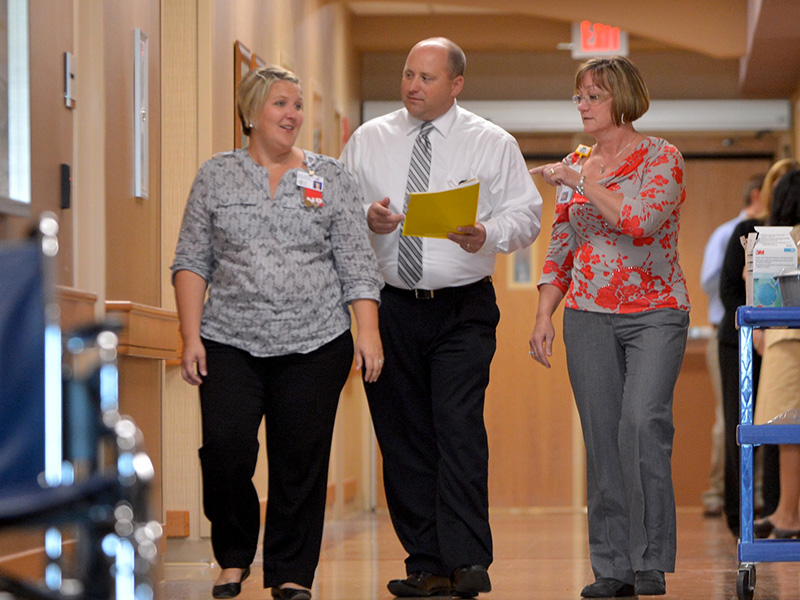 three health professions walk down a hospital hallway
