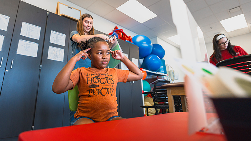OTD student working with a child in a room with OT equipment