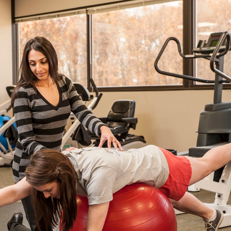 Female therapist with patient on balance ball