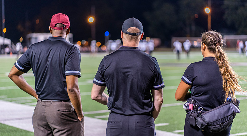 three people looking watching a football game
