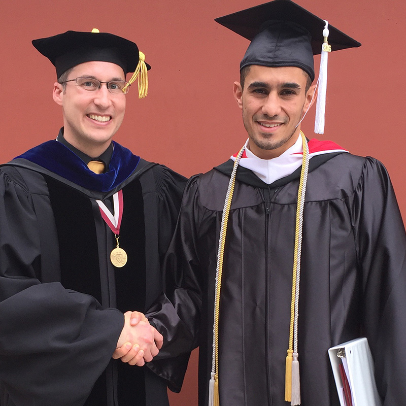 Honors College Executive Director Jim Williams with a male student in graduation cap and gown