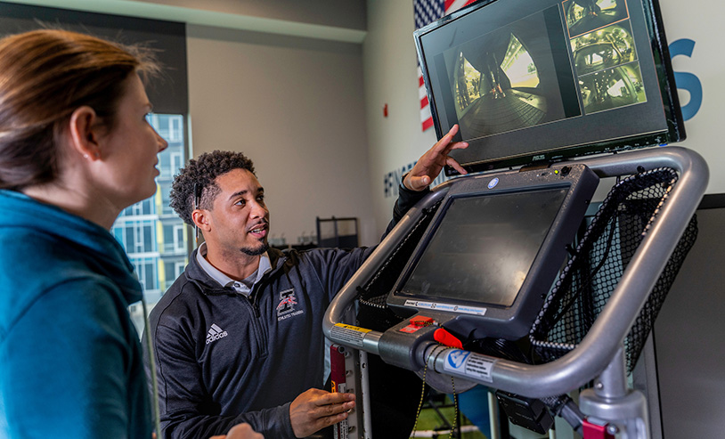 students discussing what they see on an exercise equipment