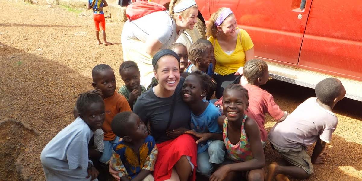 woman on a mission trip, surrounded by smiling children