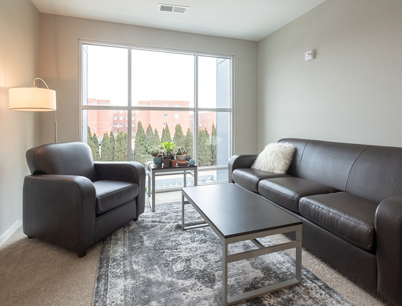 living room a sofa, chair, coffee table, and floor lamp next to a large window.